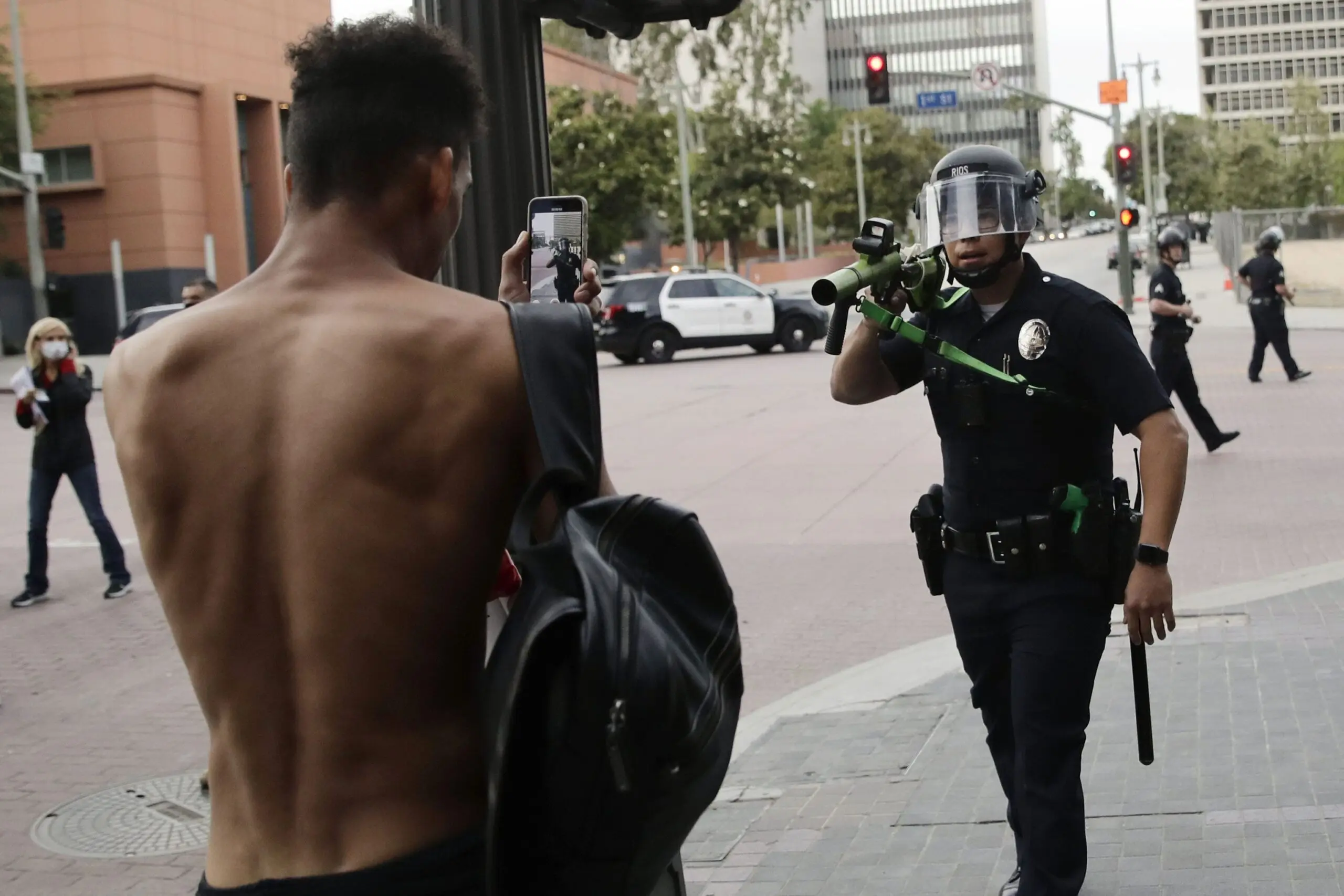 A Los Angeles police officer aims his less-lethal weapon at a demonstrator during a June 2020 protest.
