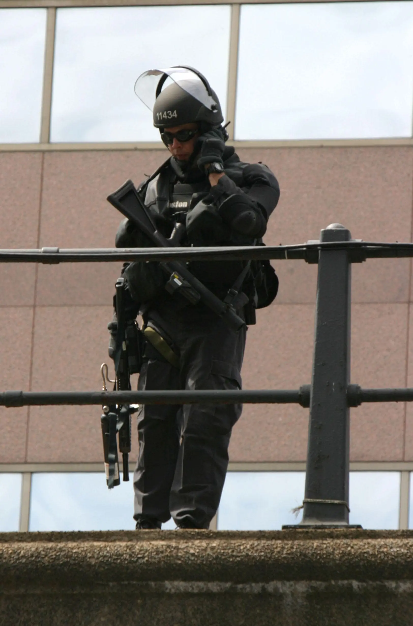 On the eve of the 2004 Democratic Convention in Boston, a Boston Police officer carries an FN303 as protesters demonstrate nearby.