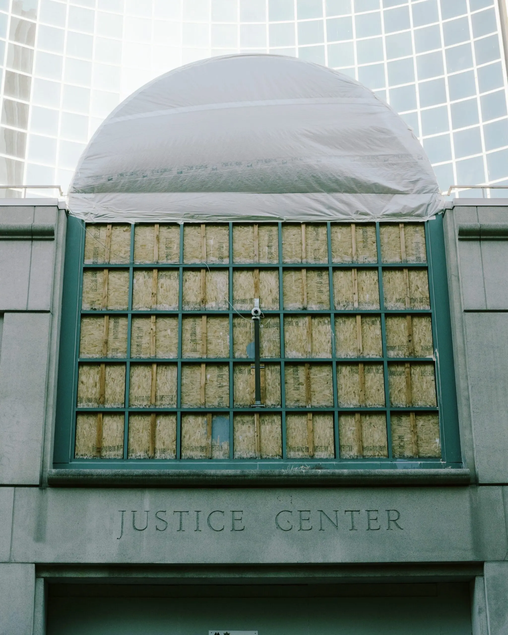 The Multnomah County Justice Center covered in tarps and boarded up with plywood.