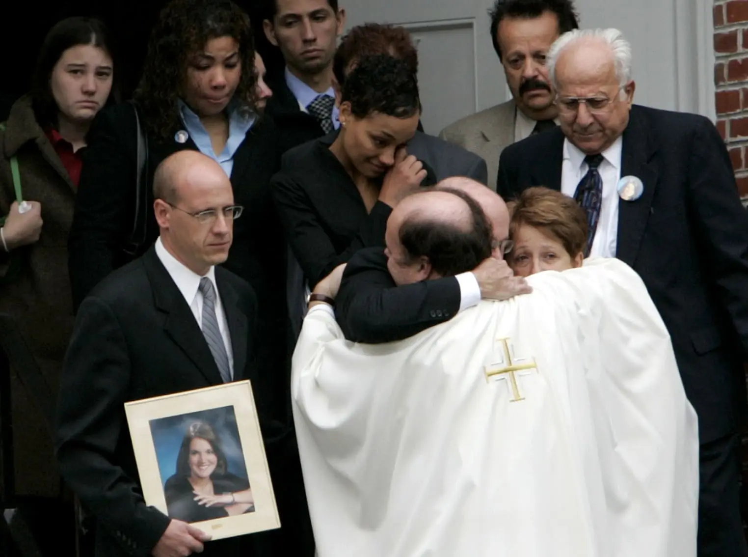 The pastor of St. Johns Church hugs Victoria Snelgroves parents, Richard and Diane Snelgrove, after their daughter's funeral service in October 2004.