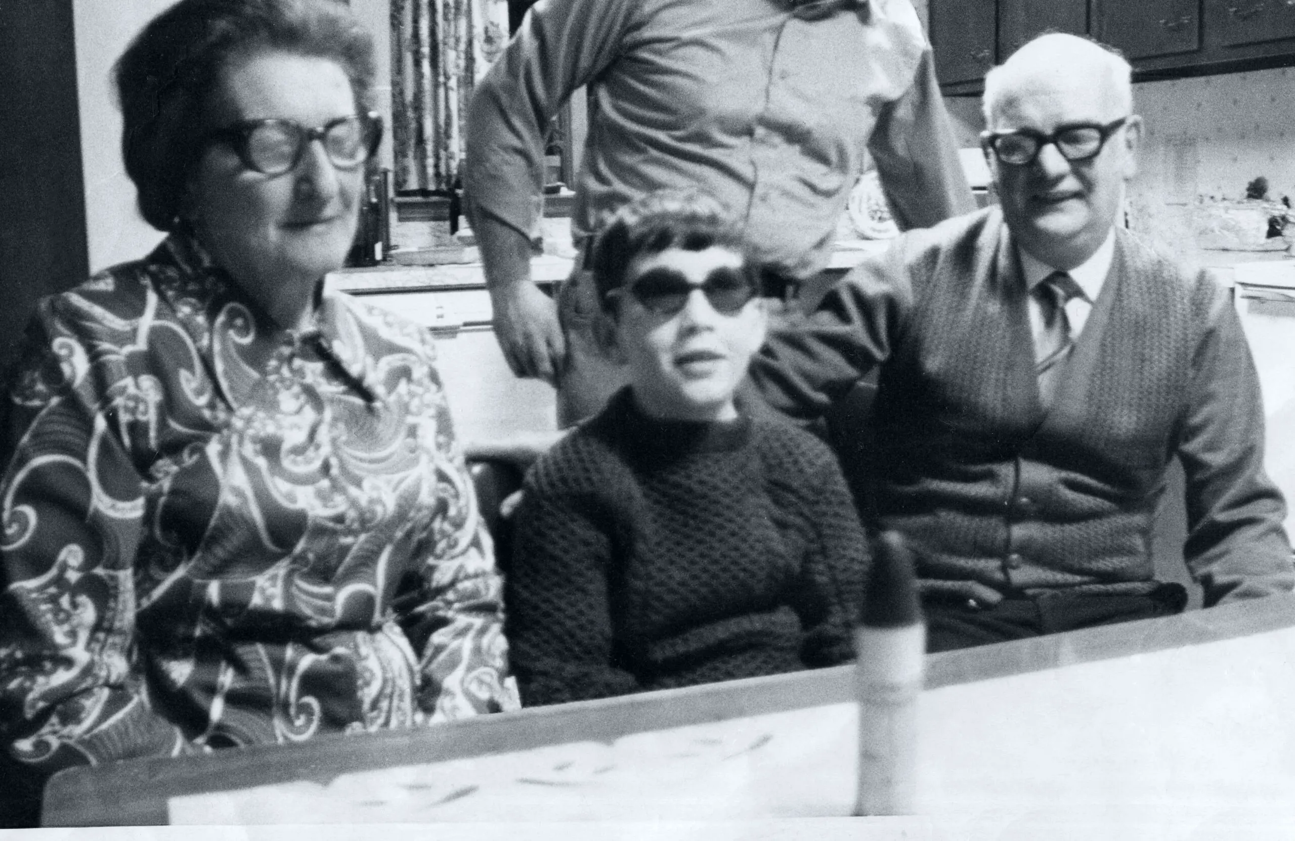 Moore with his parents in Boston, Mass., where they traveled in the hope of restoring his eyesight in January 1973. The rubber bullet that blinded him sits on the table in front of them.