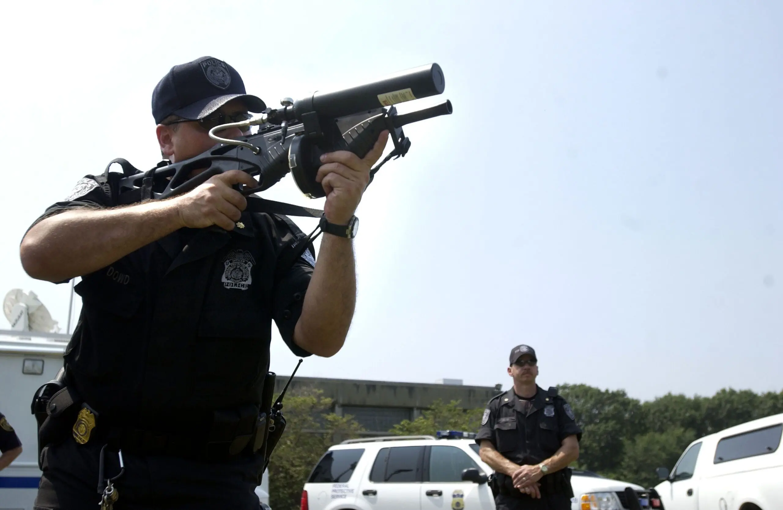 A Federal Protective Service officer fires an FN303 launcher.