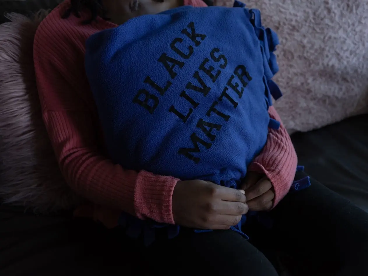 A person holds a blue pillow emblazoned with the words Black Lives Matter.